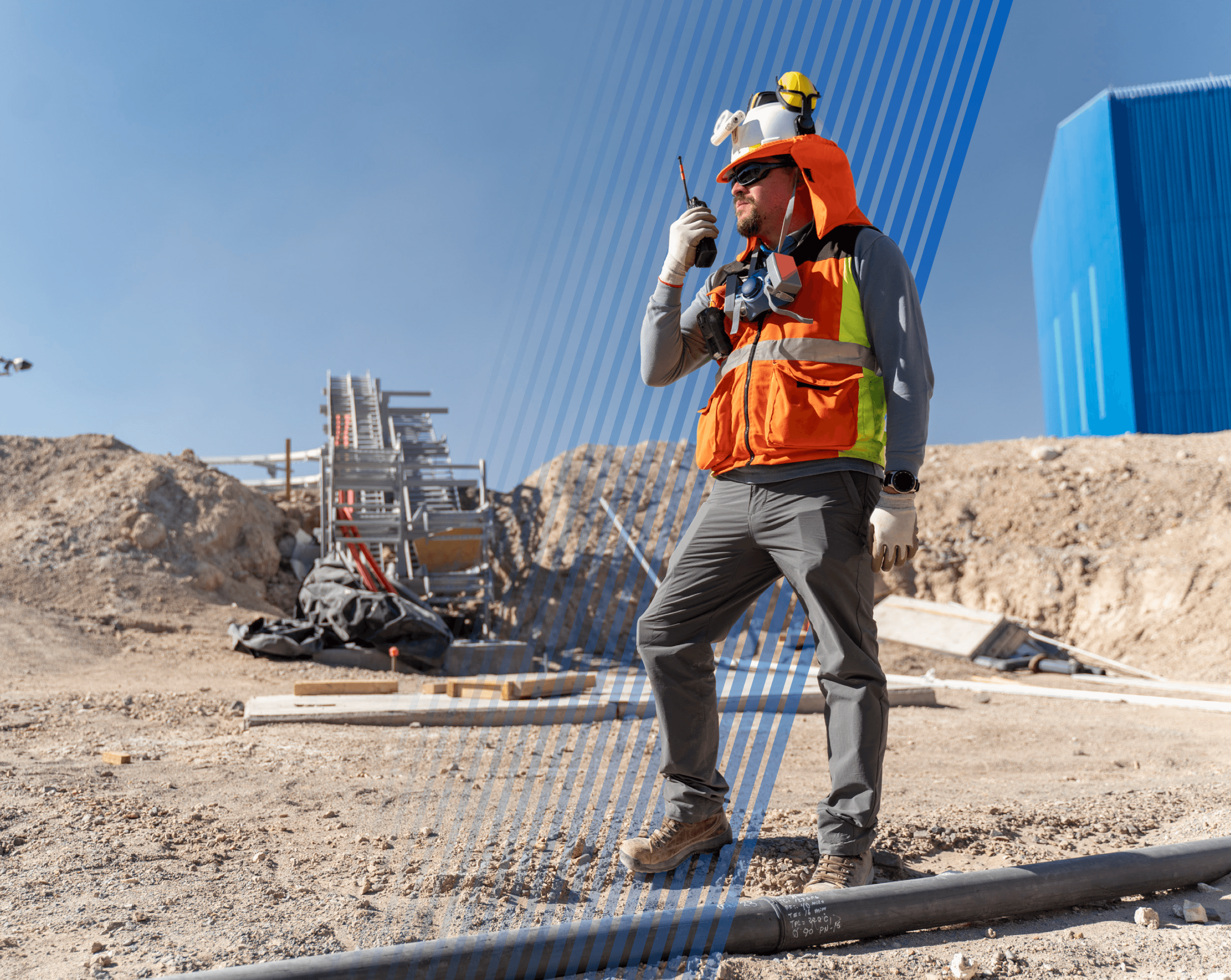 Trabajador con equipo de seguridad completo utiliza un radio en un sitio de construcción exterior.